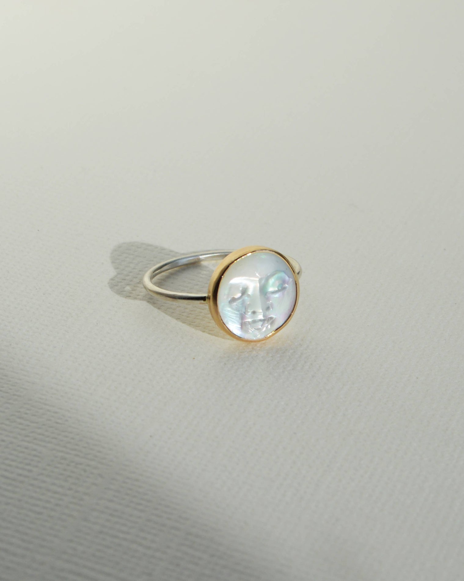 Gold ring with a clear gemstone on a light gray background, Pearl Moon Face Ring