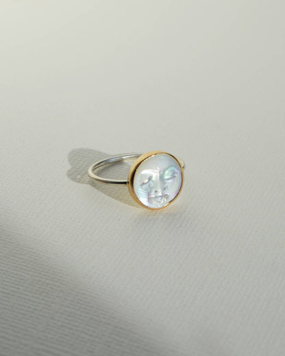 Gold ring with a clear gemstone on a light gray background, Pearl Moon Face Ring