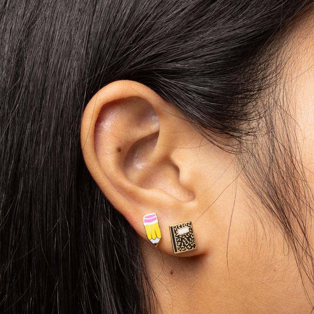 Close-up of an ear wearing a gold earring with a black pattern, hair partially obscuring the view.