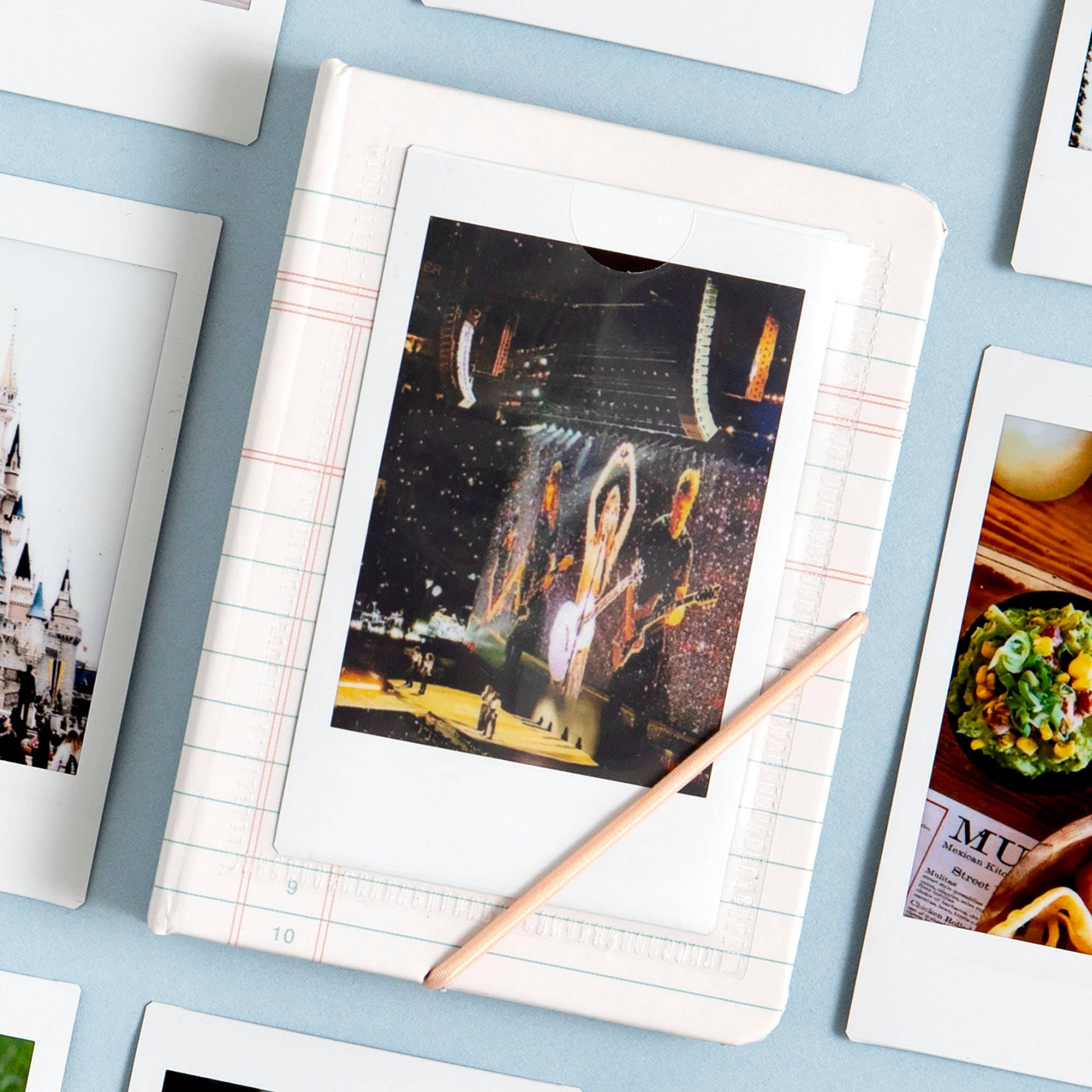 Collection of photo prints on a light blue surface with a pencil.