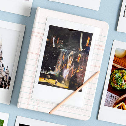 Collection of photo prints on a light blue surface with a pencil.