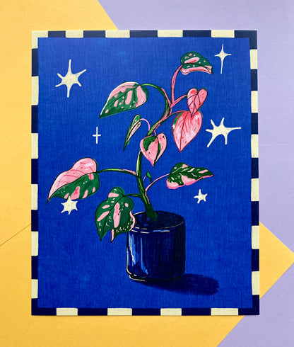 A square art print or card featuring a stylized illustration of a potted plant with pink and green variegated leaves on a deep blue background with white stars, bordered by a black and cream check pattern, set against a yellow and lavender background.