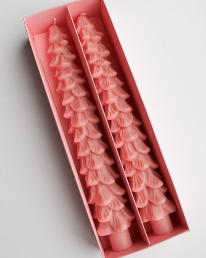 Two pink Christmas tree-shaped candles in a box on a light gray background