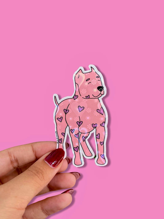 Sticker of a pink dog with heart patterns held against a pink background