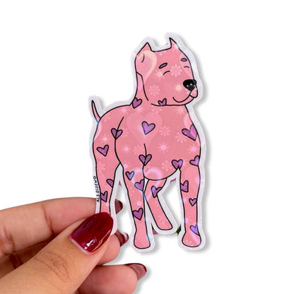 Pink dog sticker with heart patterns held by a hand on a white background