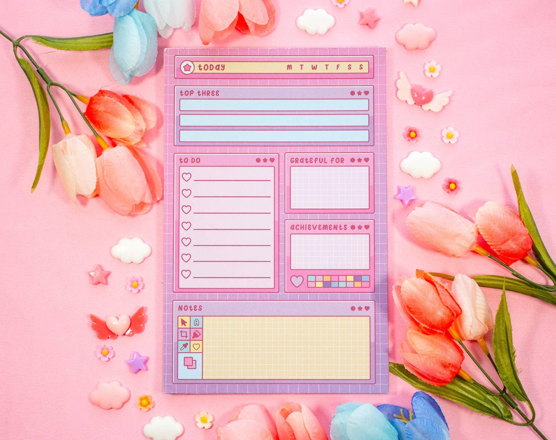 Notepad with a digital interface design surrounded by flowers on a pink background