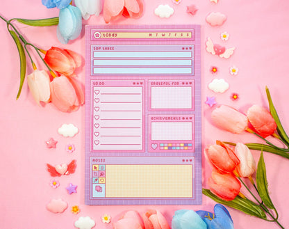 Notepad with a digital interface design surrounded by flowers on a pink background