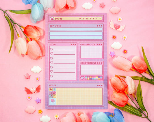 Notepad with a digital interface design surrounded by flowers on a pink background