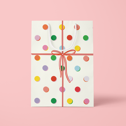 Gift card with colorful polka dots and a red ribbon on a pink background