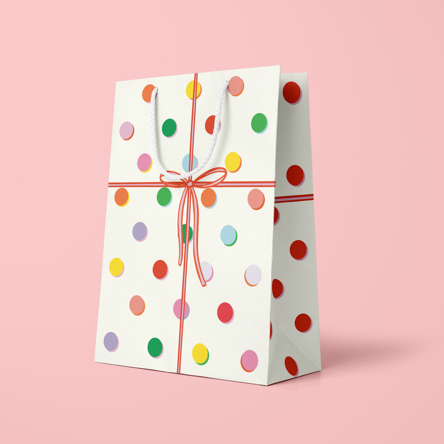 Gift bag with colorful polka dots on a pink background