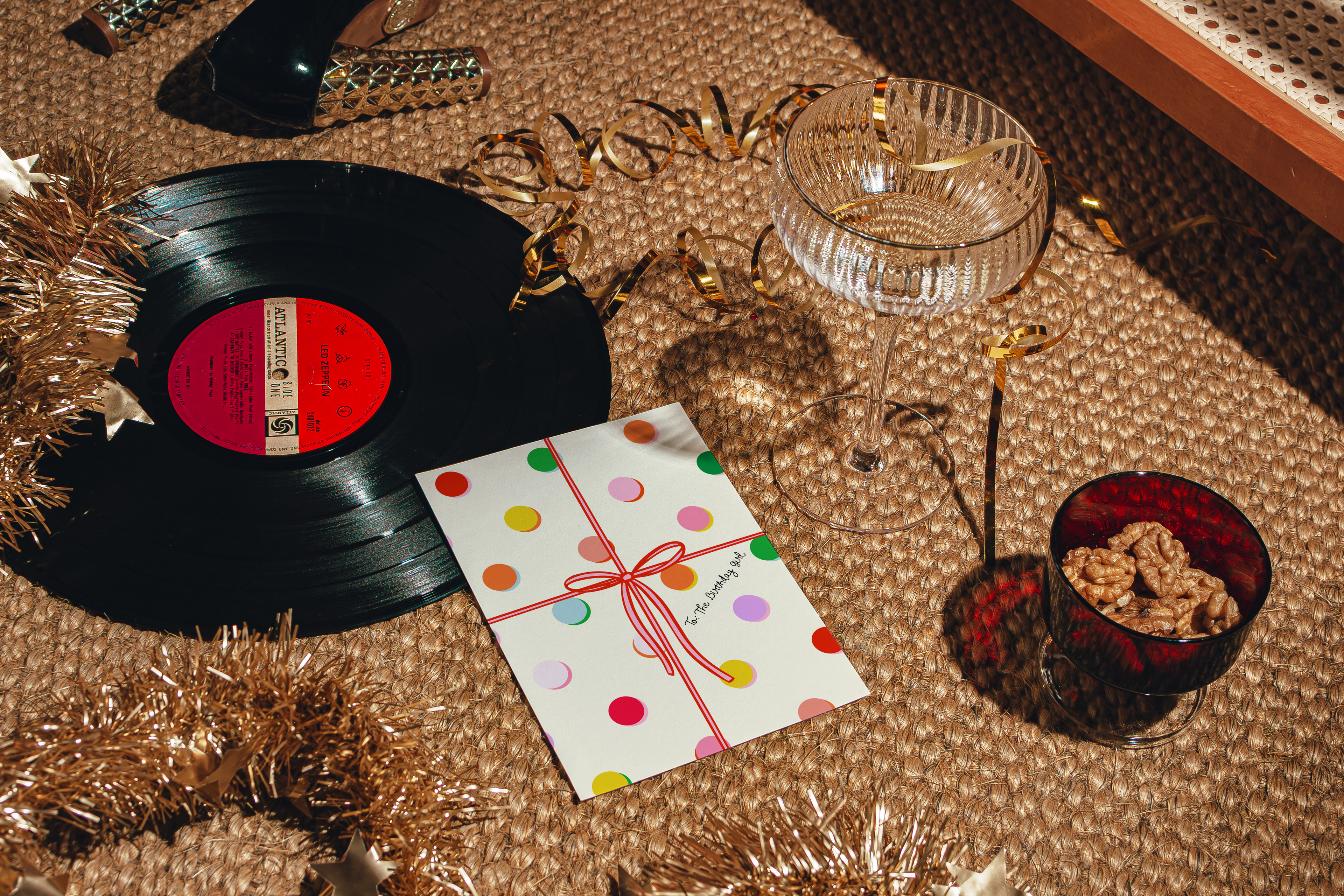 Vinyl records, a glass, and a card on a textured surface with decorative elements.
