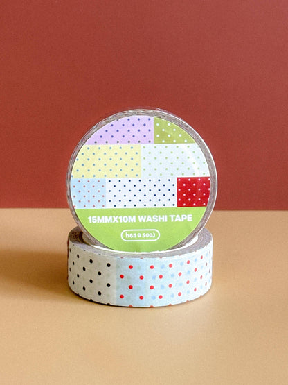 Two rolls of washi tape with colorful patterns on a beige surface and red background