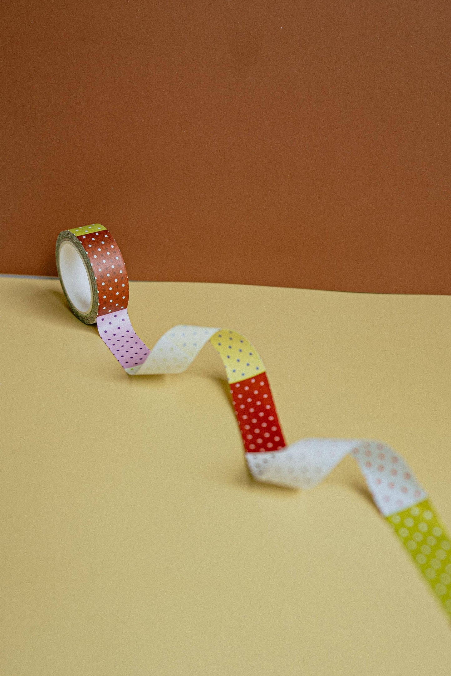 Colorful washi tape roll on a beige surface with a brown background