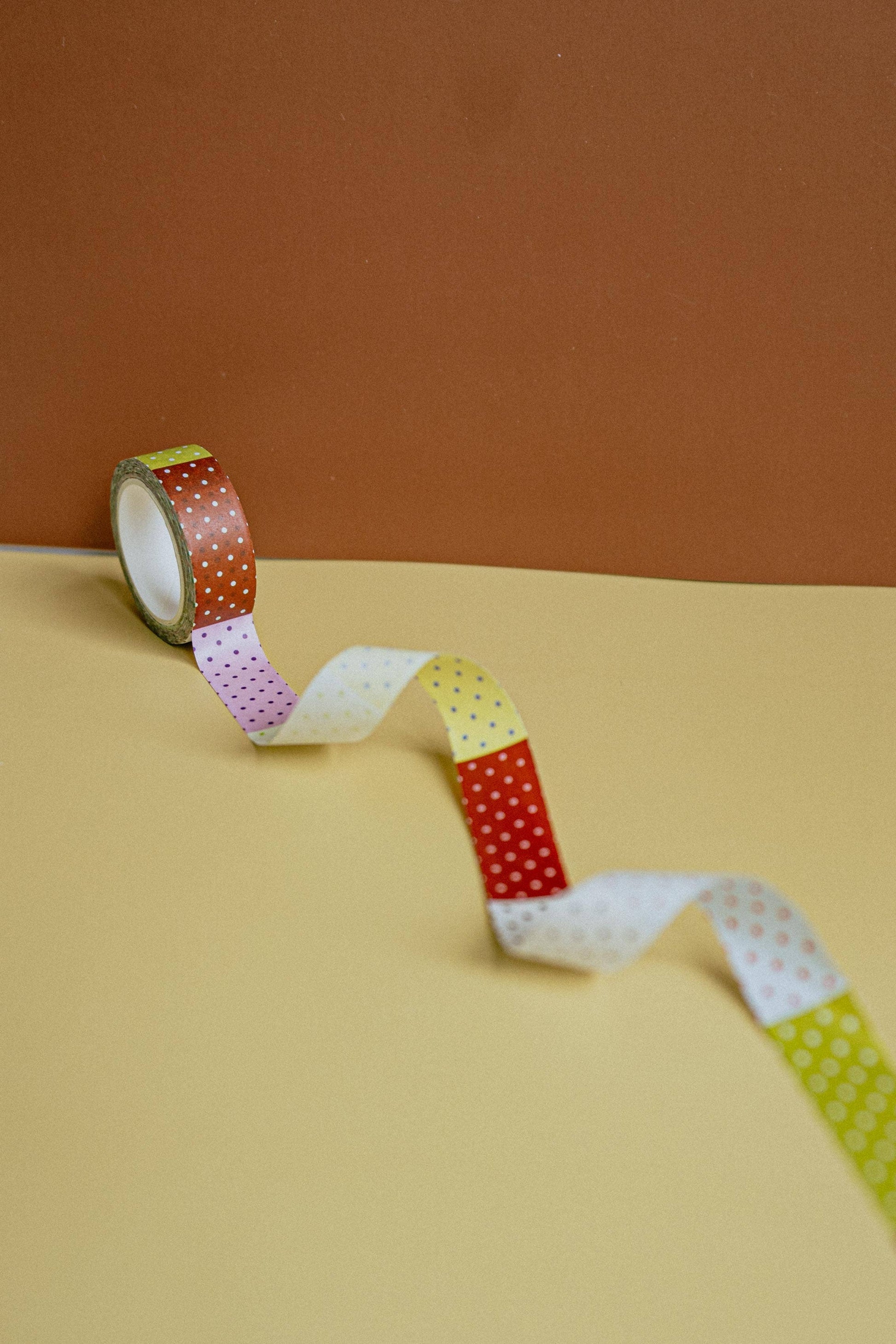 Colorful washi tape roll on a beige surface with a brown background