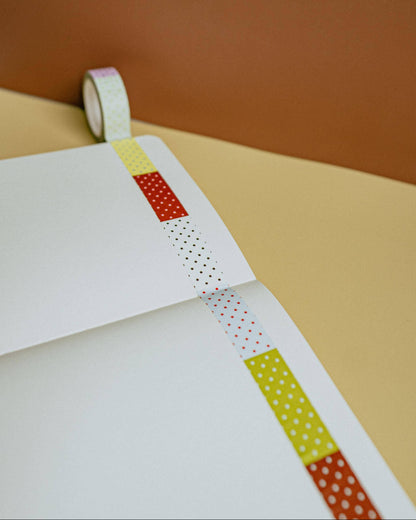 Washi tape with colorful patterns on a white surface against a brown background