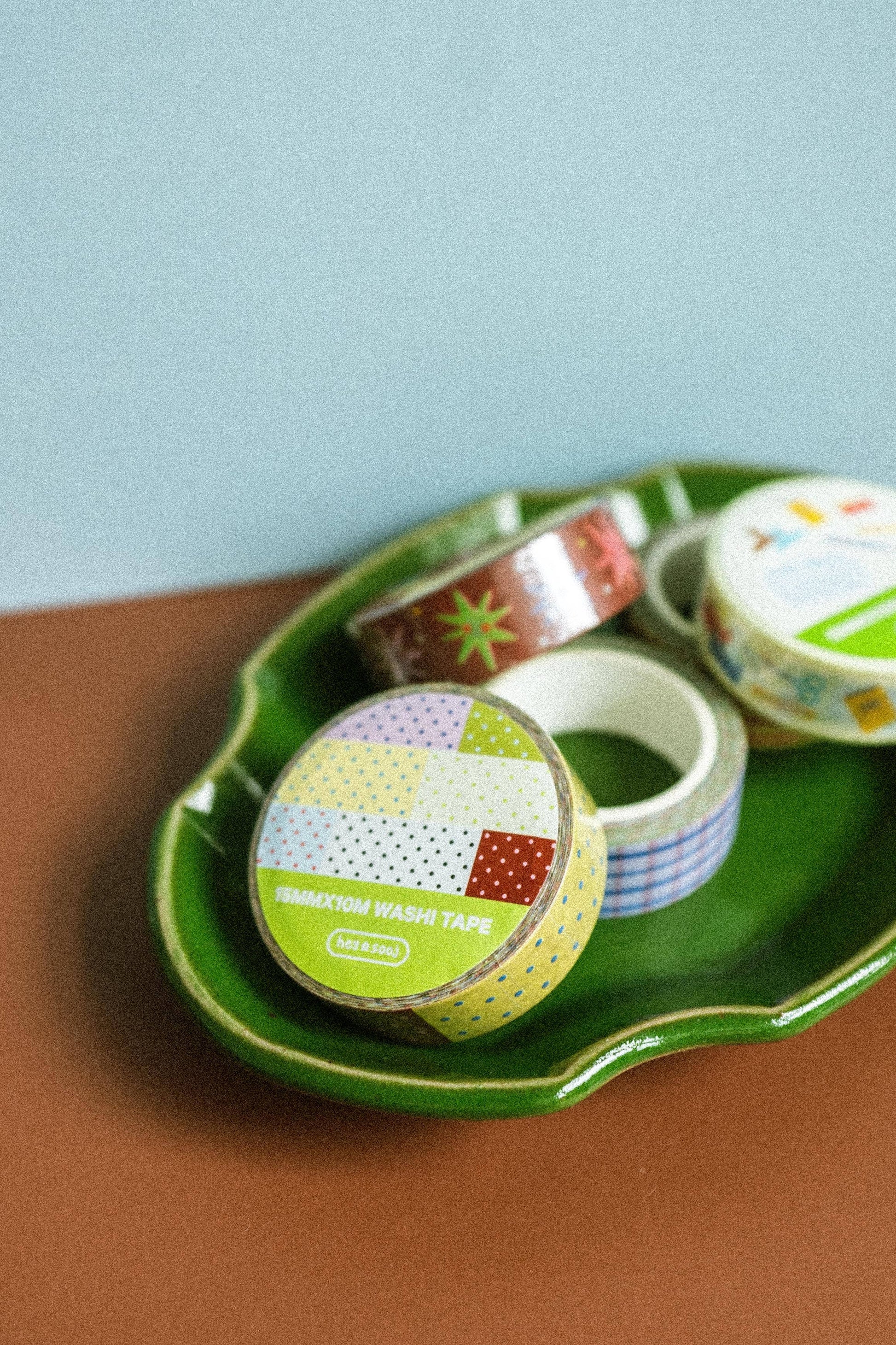 Three rolls of washi tape on a green tray with a light blue background