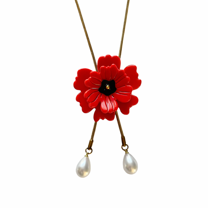 Red flower pendant with white beads on a gold chain against a white background
