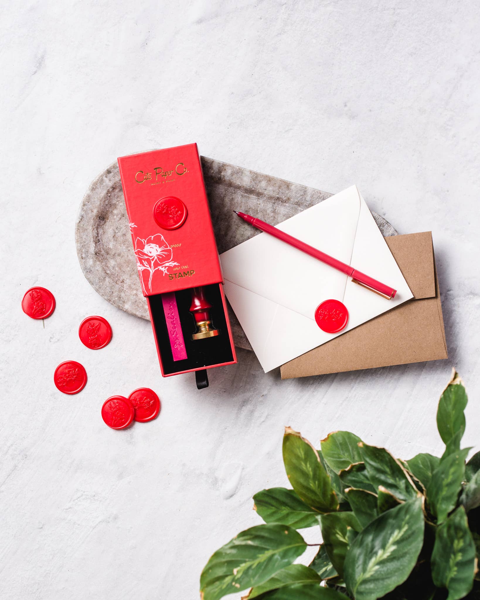 Red wax seal set with matching envelope and sealing wax on a light surface.