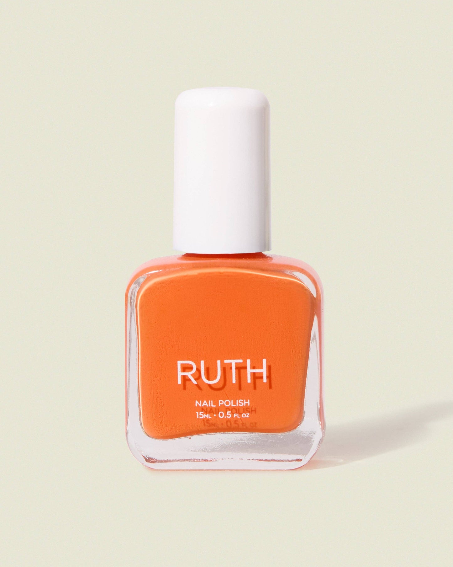 Orange nail polish bottle with white cap on a light beige background, Ruth Nail Polish White 