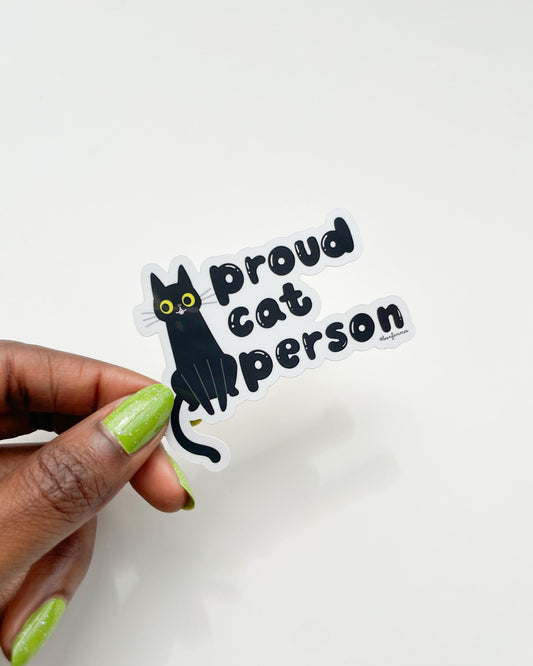 Sticker with a black cat illustration and 'Proud Cat Person' text held by a hand with green nail polish on a white background. Proud Cat Person Sticker bon femmes