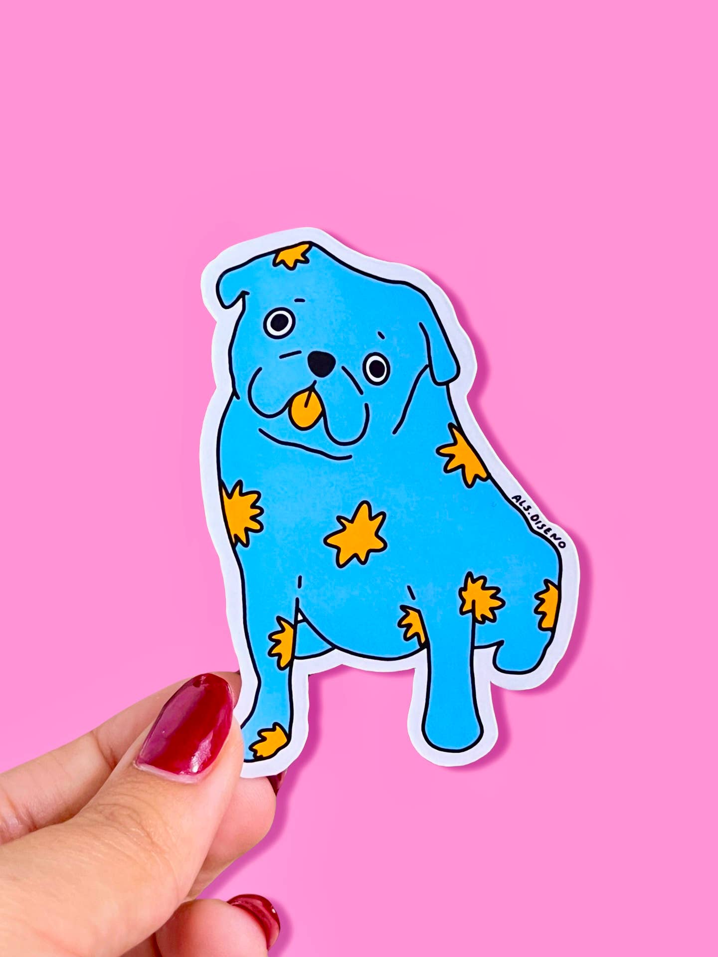 Blue dog-shaped sticker with yellow stars held by a hand against a pink background