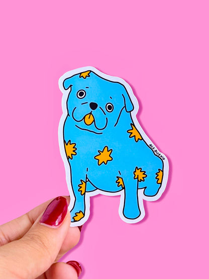 Blue dog-shaped sticker with yellow stars held by a hand against a pink background
