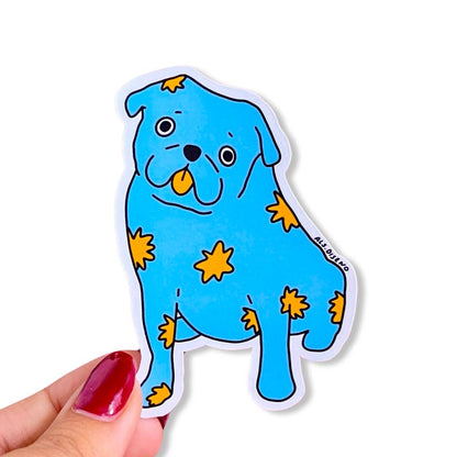 Blue dog-shaped sticker with yellow spots held by a hand on a white background