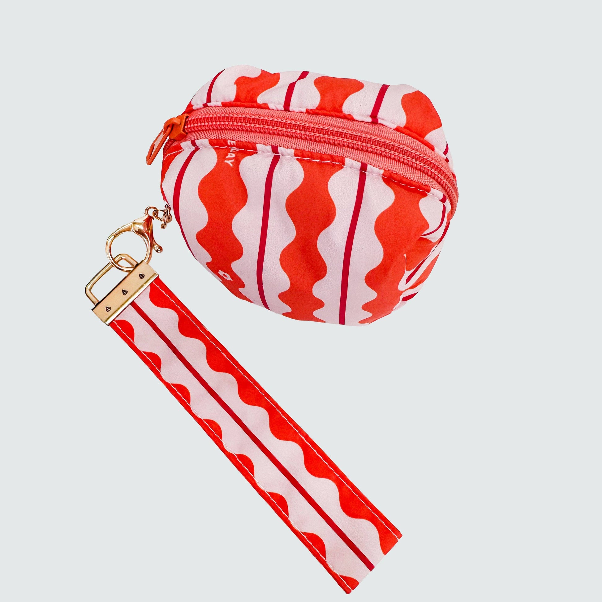 Small round pouch with red and white wave pattern and matching strap on a light gray background