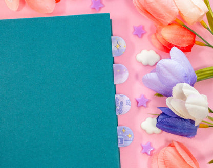 Teal notebook on a pink background with decorative flowers and stars