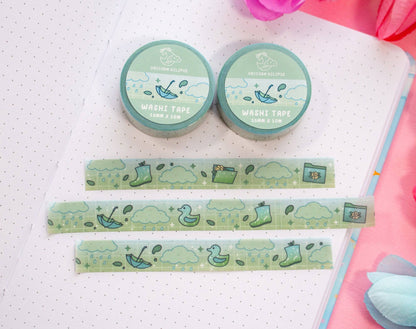 Two rolls of green washi tape with cartoon designs on a white surface.