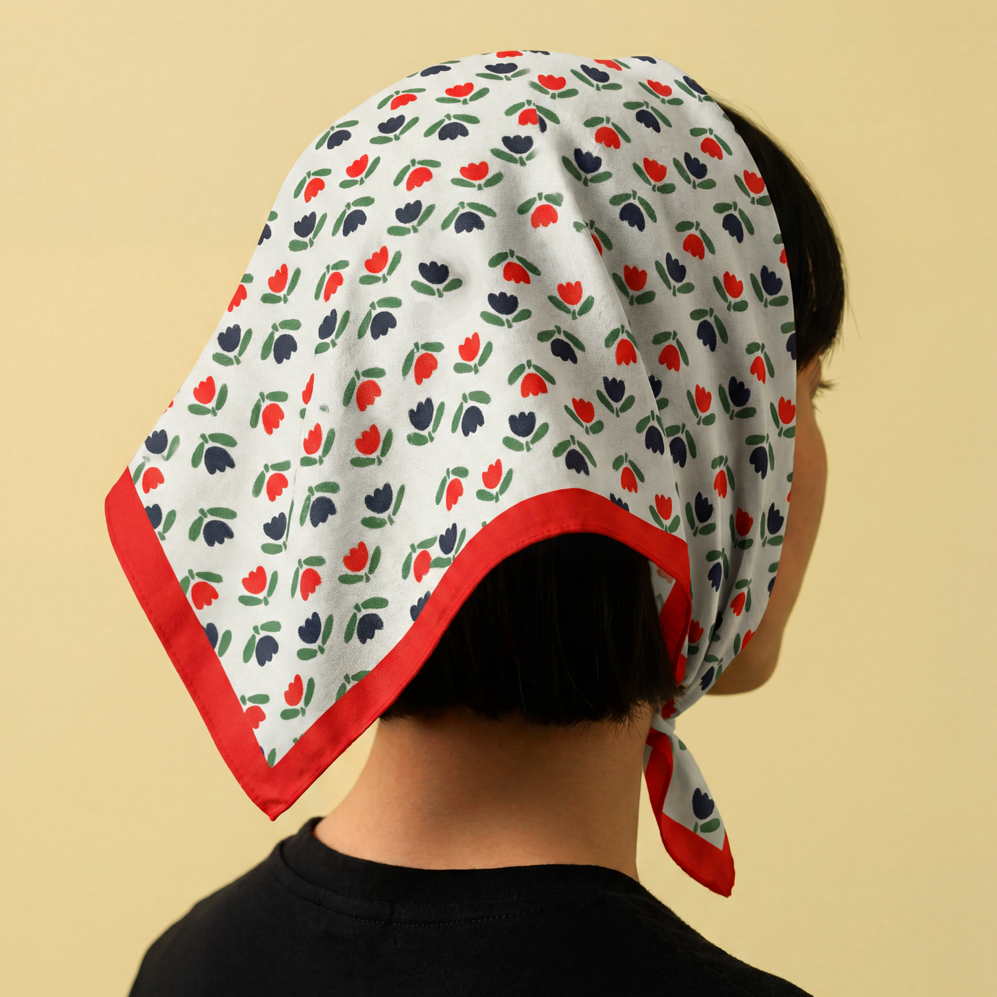 Person wearing a floral patterned headscarf on a beige background