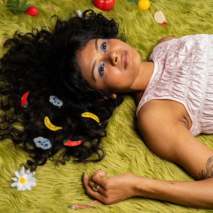 Woman lying on a green textured surface with colorful hair accessories