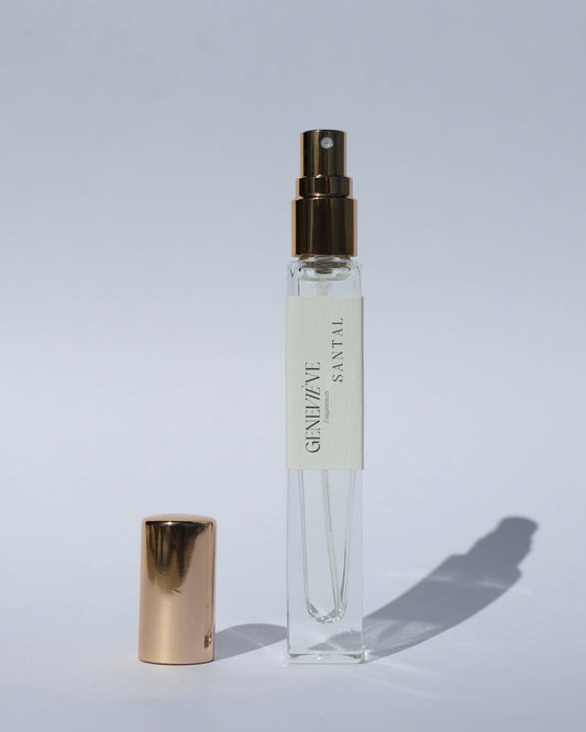 Small clear perfume bottle with gold cap on a light gray background
