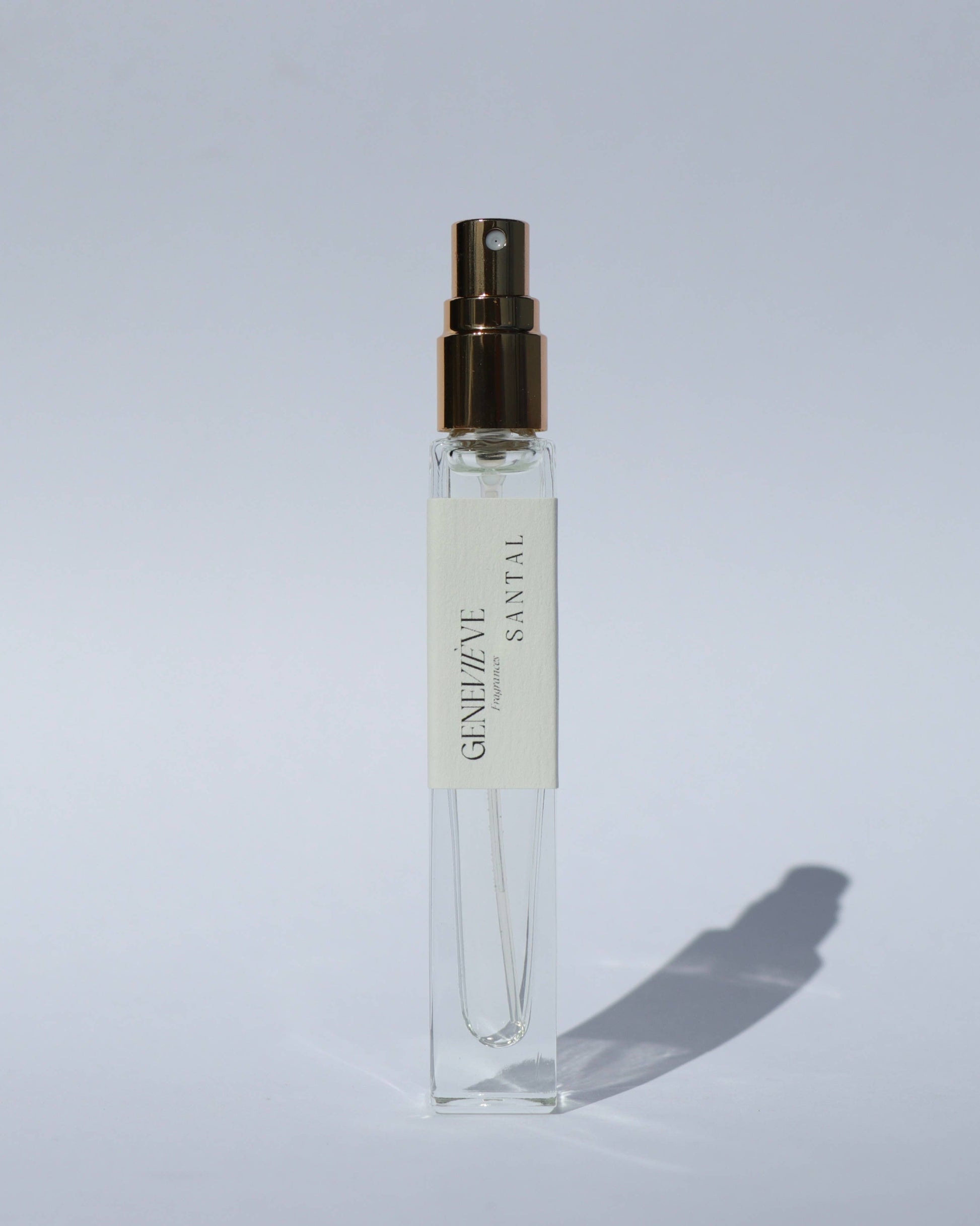 Small clear spray bottle with a gold cap on a light gray background