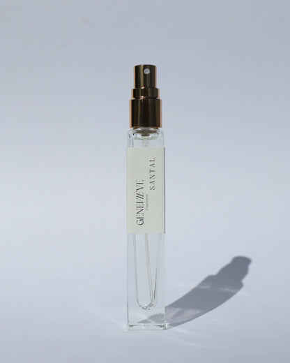 Small clear spray bottle with a gold cap on a light gray background