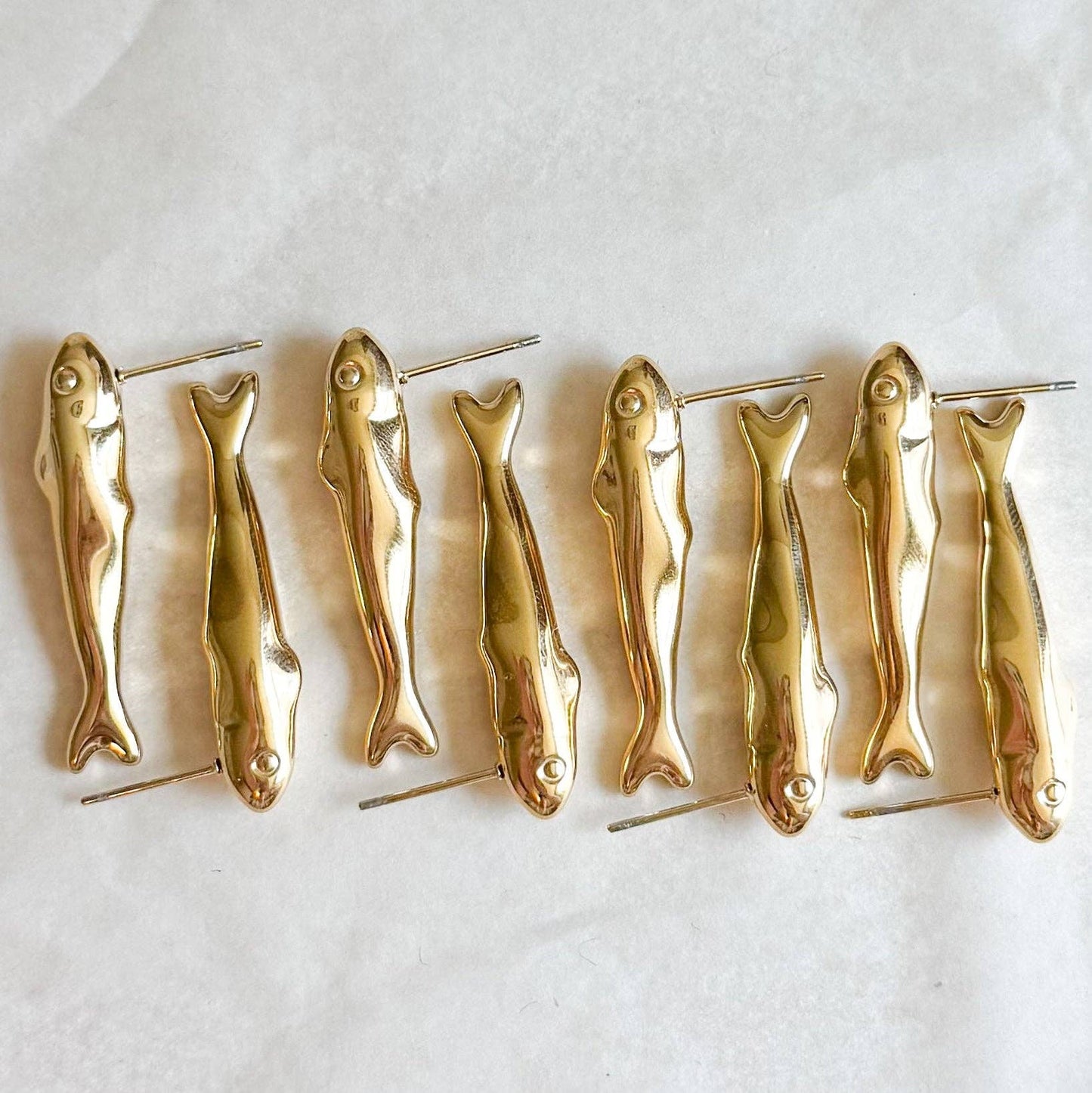 Set of gold fish-shaped earrings on a white background