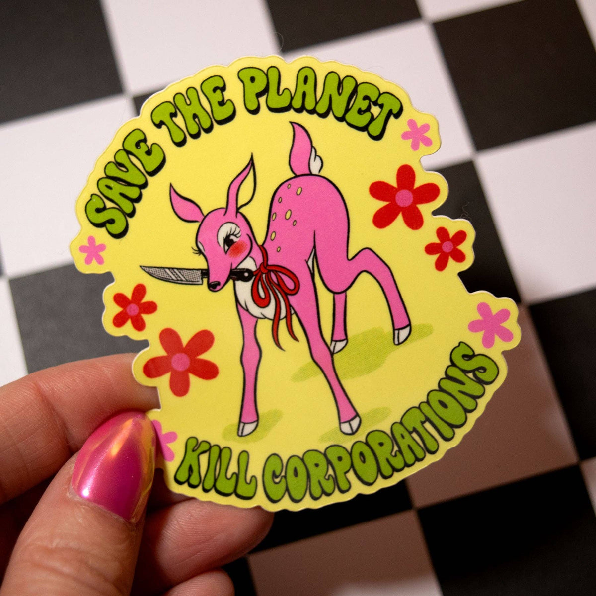 A hand with pink nail polish holds a die-cut sticker featuring a pink fawn with a knife and the text 'SAVE THE PLANET' and 'KILL CORPORATIONS'. The sticker has a yellow background with red and pink flowers.