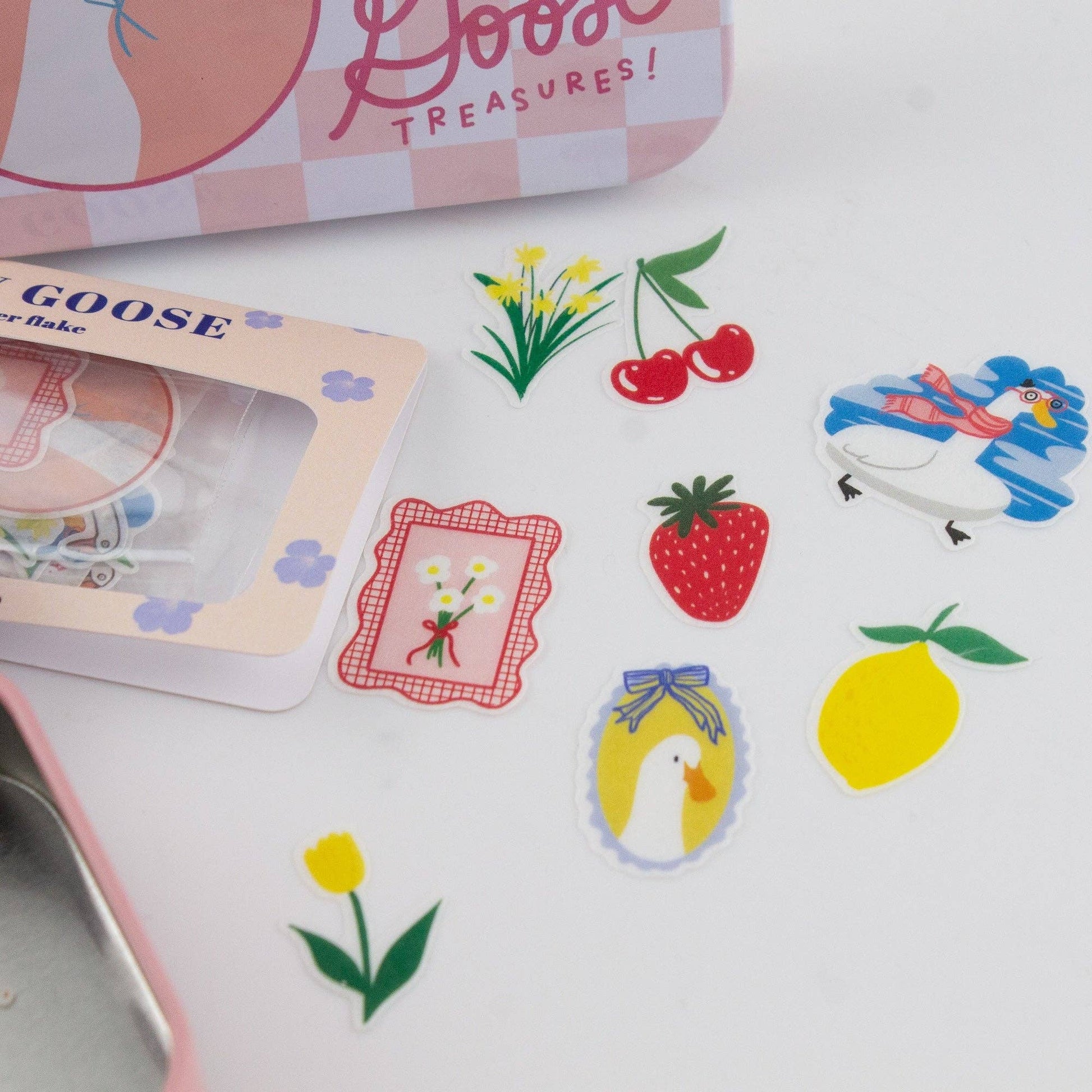 Set of colorful stickers featuring a goose, strawberry, lemon, and other designs on a white surface.