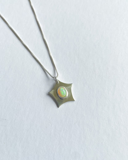 Silver necklace with a star-shaped pendant featuring an opal stone on a light gray background