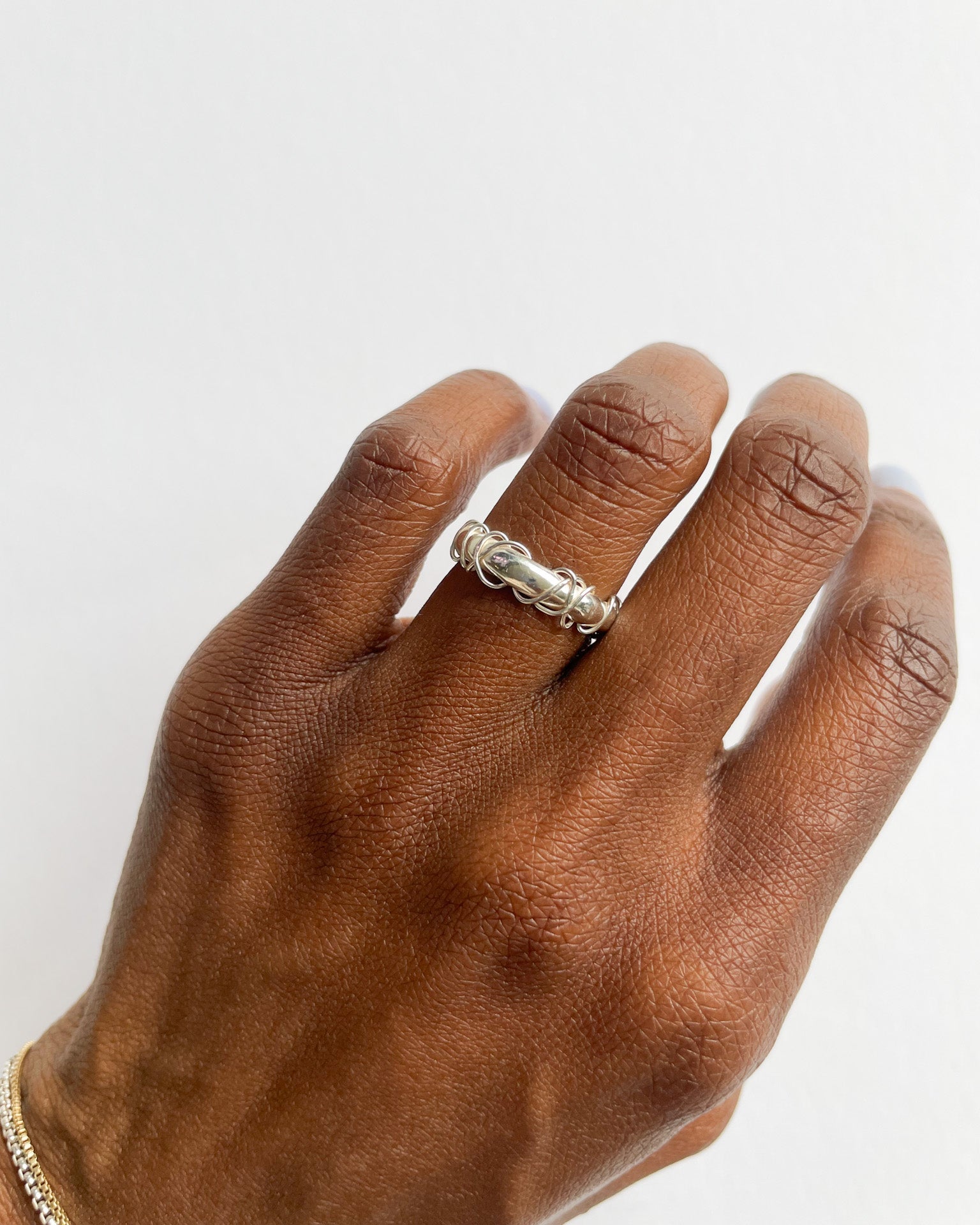 Hand wearing a silver ring on a white background