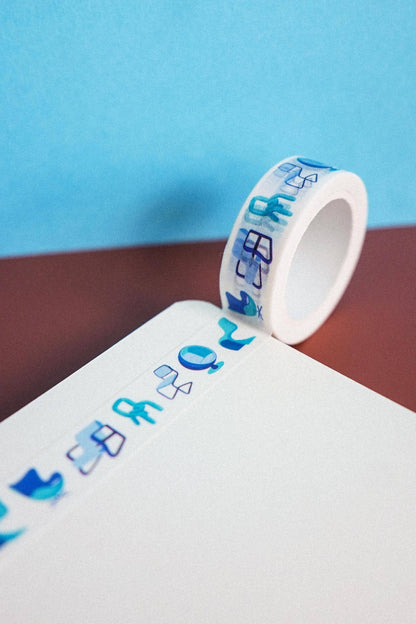 Roll of decorative tape with blue designs on a white surface against a blue background