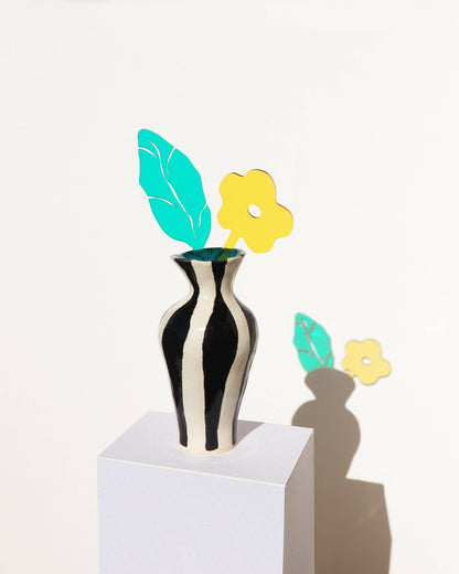 Black and white striped vase with decorative flowers on a white background