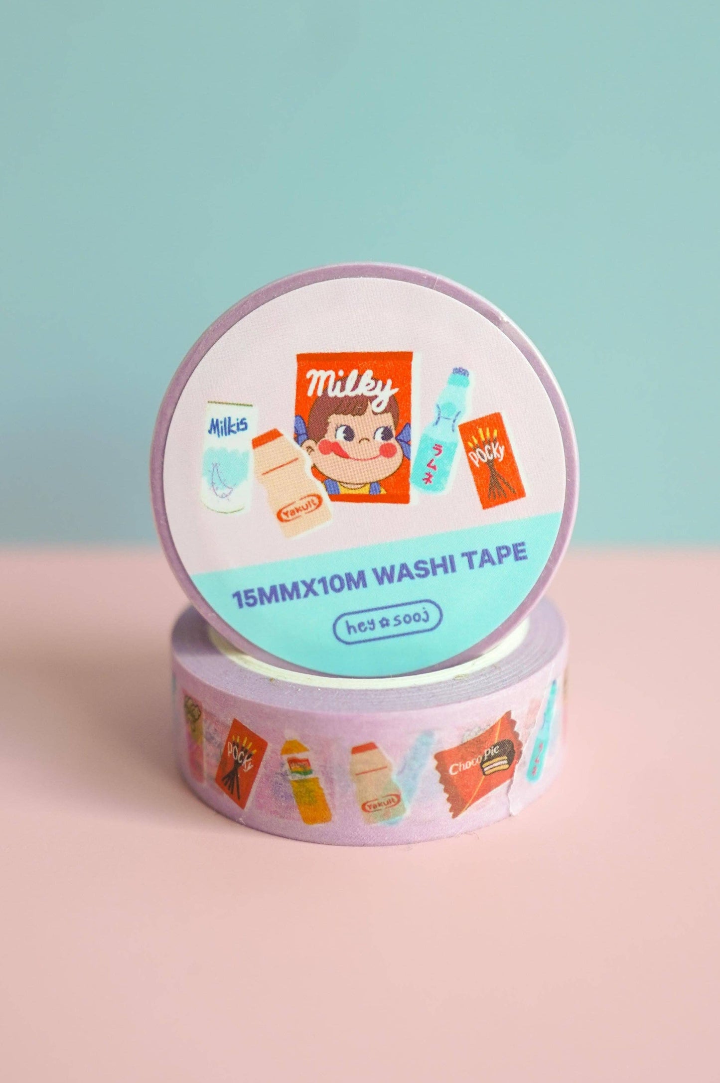 Roll of Milky washi tape with colorful designs on a pink surface and light blue background