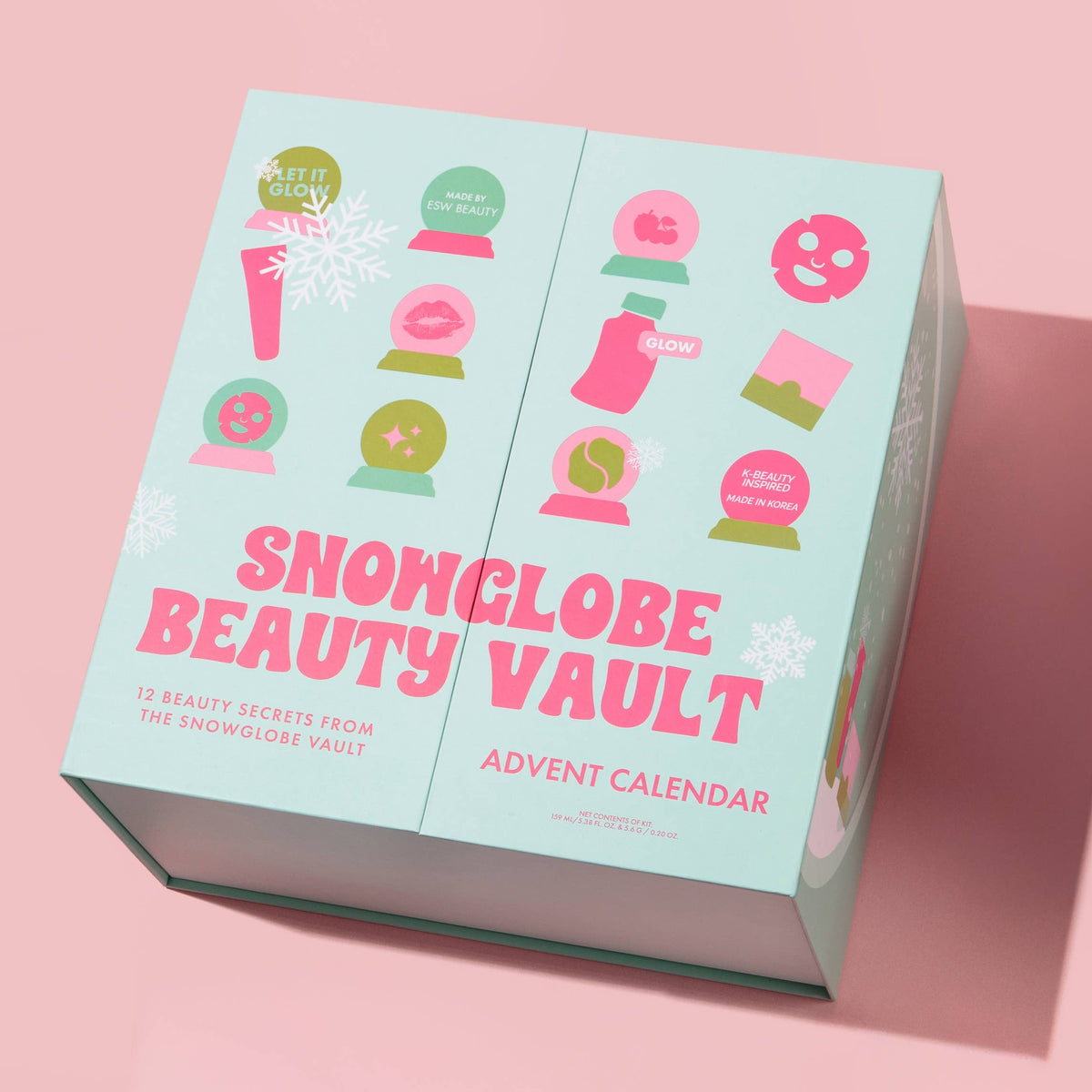 A boxed advent calendar product titled 'SNOWGLOBE BEAUTY VAULT' shown at an angle on a pink background. The box is pale mint/aqua with large pink title text and illustrated snow globe icons in pink, green, and white.