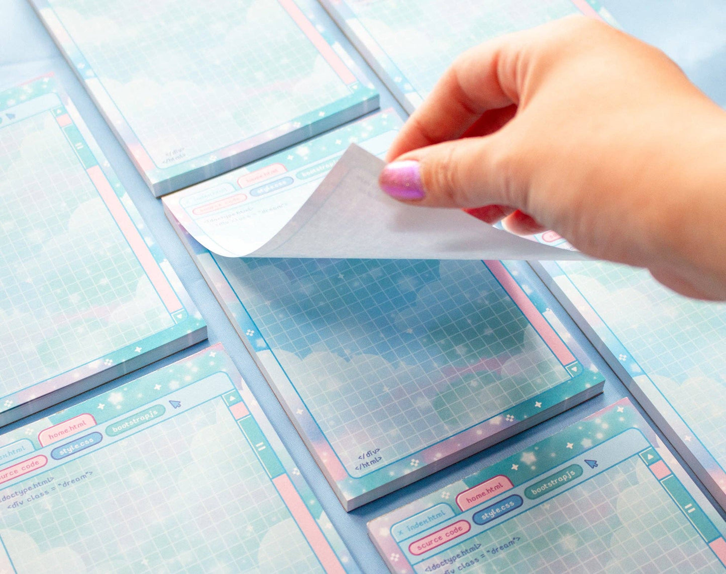 Hand holding a transparent sheet over a stack of colorful planner stickers with grid and design elements.