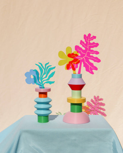 Colorful geometric planters with leaf-shaped tops on a light blue surface against a beige background