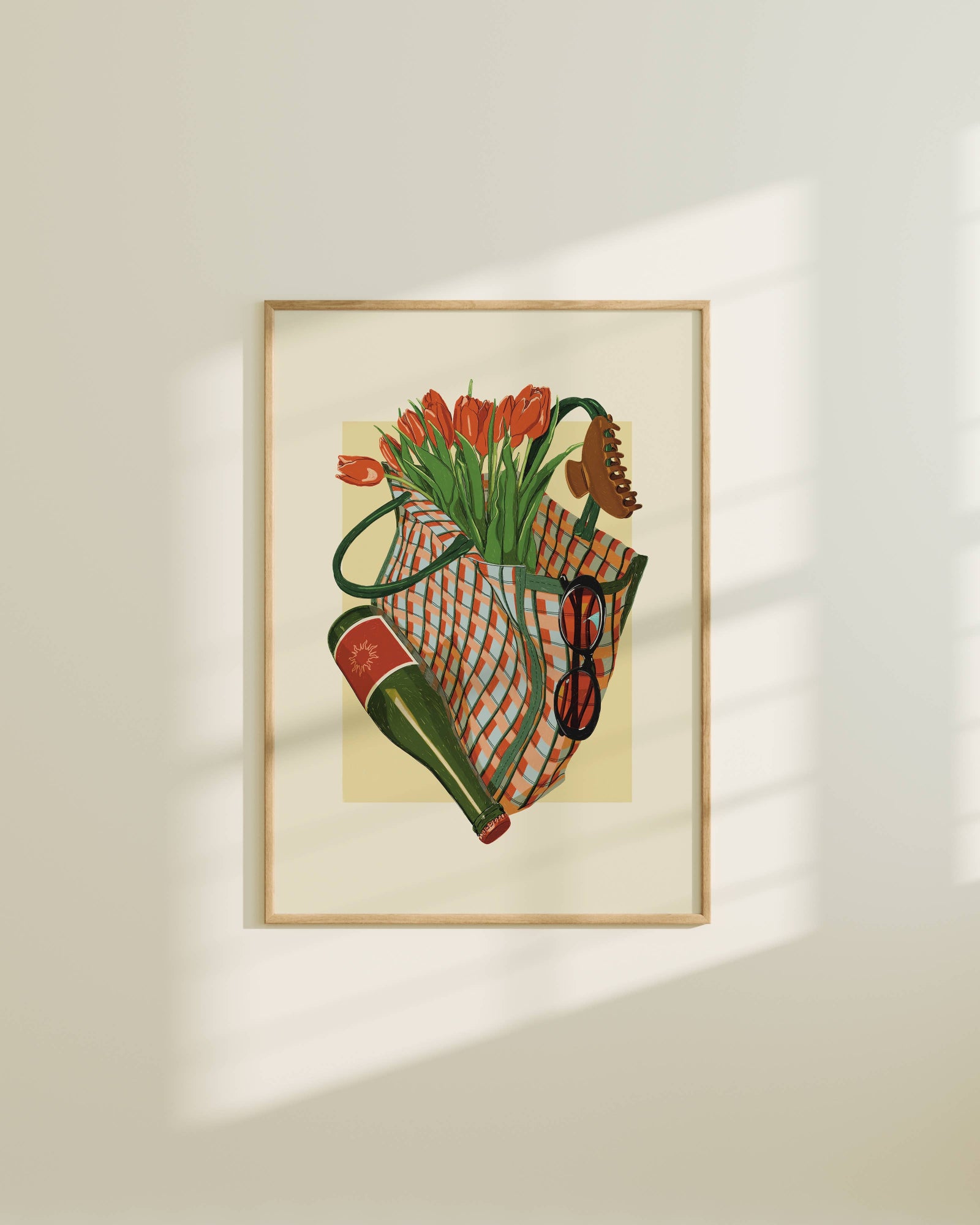 Framed artwork of a still life with flowers and a bag on a beige wall.