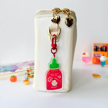 Small white pouch with a hot sauce bottle keychain on a light background