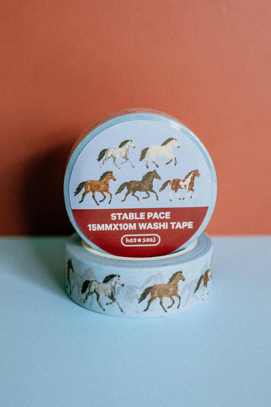 A roll of washi tape with a horse pattern, stacked on top of another roll. The top roll has a light blue label with illustrations of horses and a red band reading 'STABLE PACE 15MMX10M WASHI TAPE' and the brand 'horse soo'.