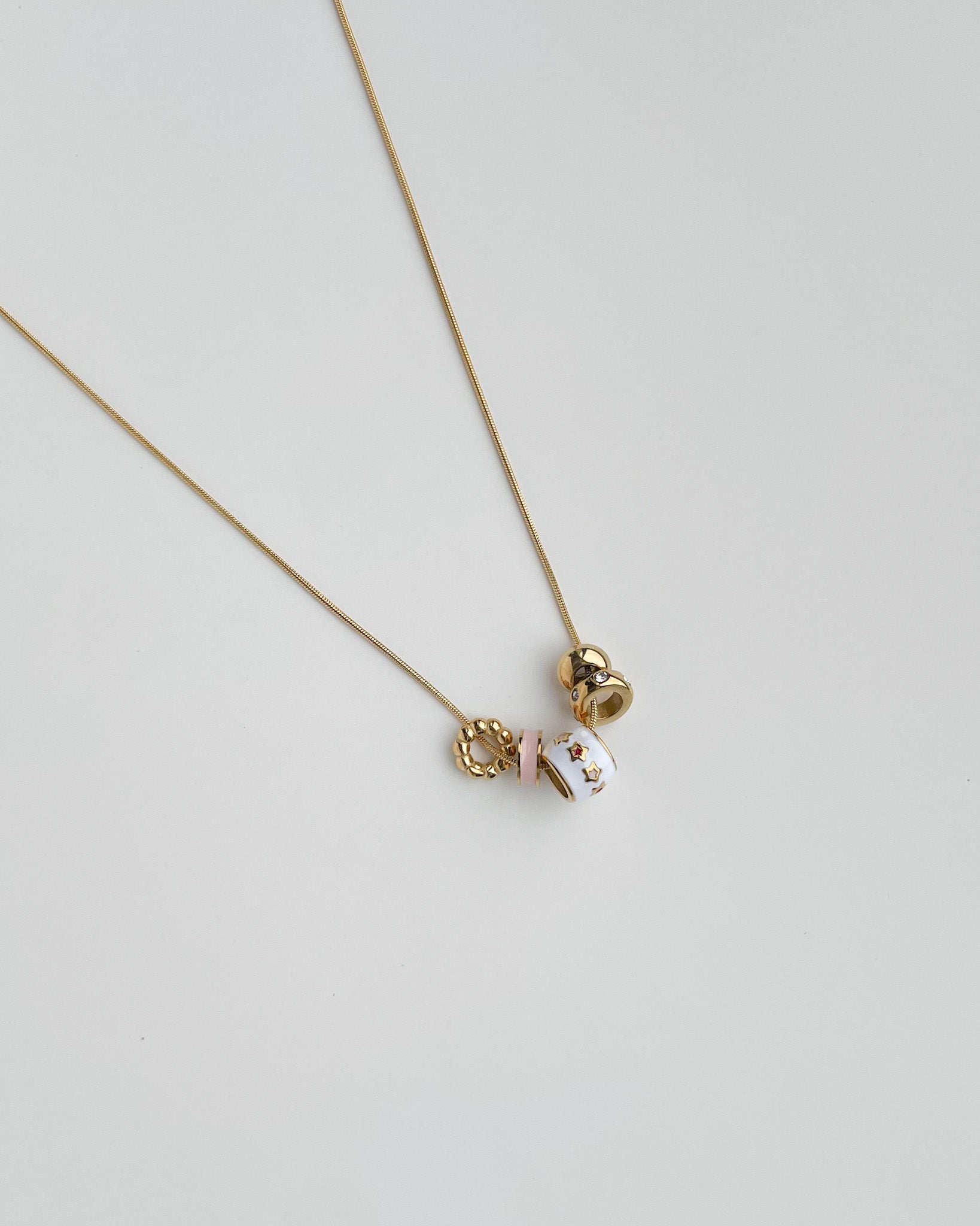 Necklace with a small pendants on a light gray background. Starry Baubles Necklace